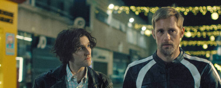 Still from Pillion of two men walking down a street together.