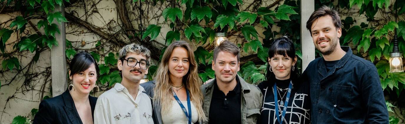 Heather and fellow students from the CICAE course posing for a course. They're all dressed smartly and are standing in front of a wall covered in leaves and ivy.