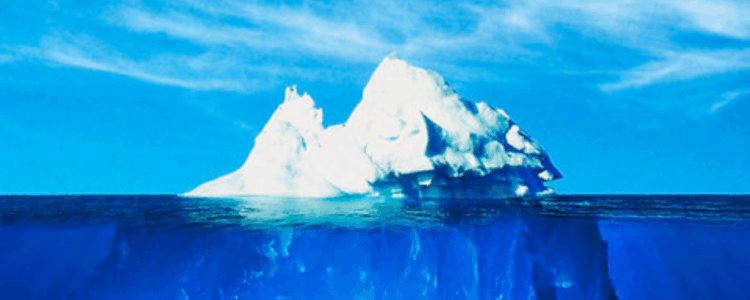 A large iceberg. The crest of the iceberg sticks out of water, whilst a much larger part is hidden beneath the surface