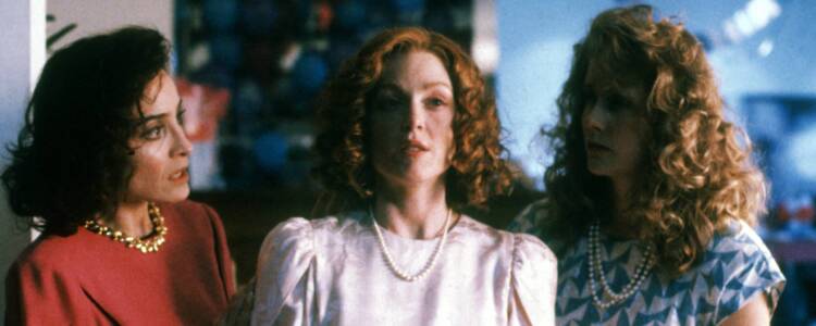 Still from SAFE. Three women in 80s-era clothing stand close to each other. The woman in the middle looks out, whilst the two on either side look at her, concerned.