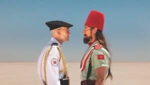Still from Straight Circle. Two men in different military uniforms stand face-to-face, staring each other down