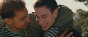 Still from LURKER of two young men with their arms around each other.
