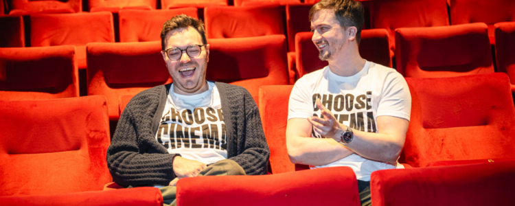 Two people in a cinema wearing t-shirts that say "Choose Cinema"